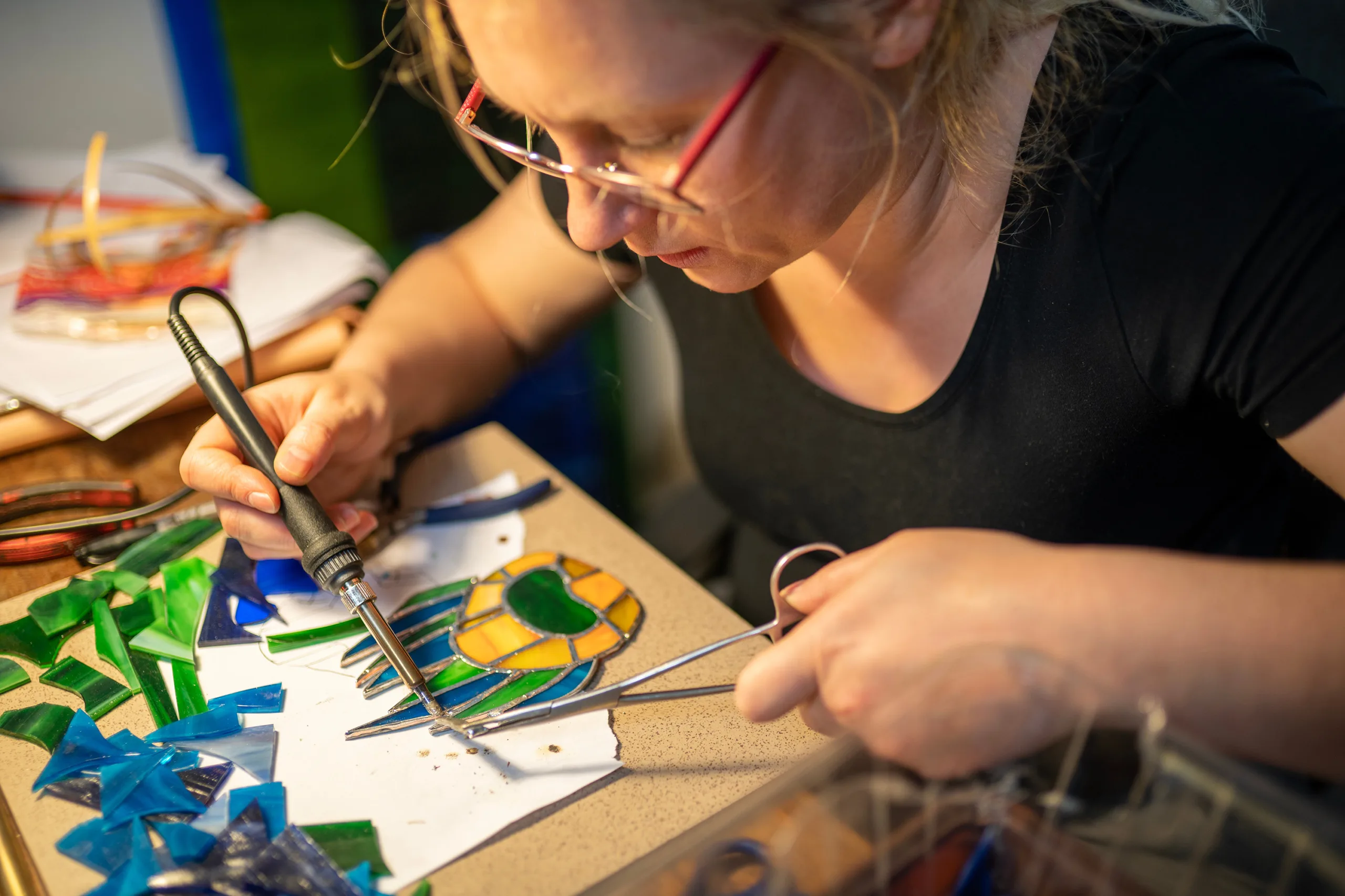 A glassblower's hands fusing colored panels in a working studio.